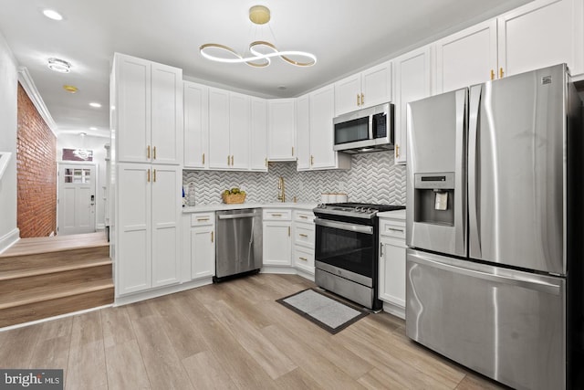 kitchen featuring white cabinetry, stainless steel appliances, light wood finished floors, decorative backsplash, and light countertops