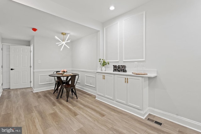 dining room with a decorative wall, visible vents, and light wood-type flooring