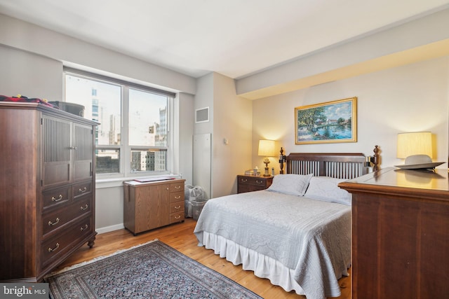 bedroom with light wood-style floors and visible vents