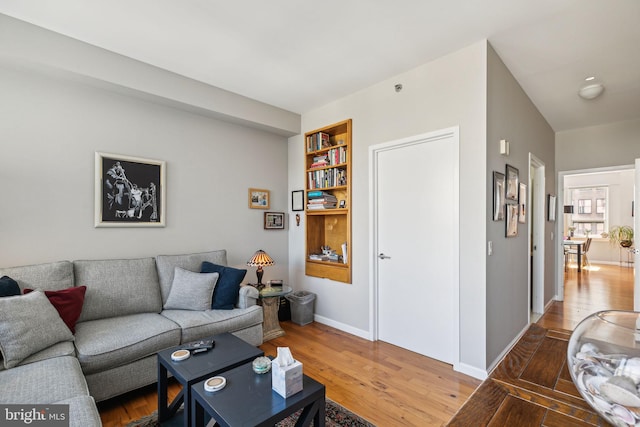 living area with built in features, baseboards, and wood finished floors