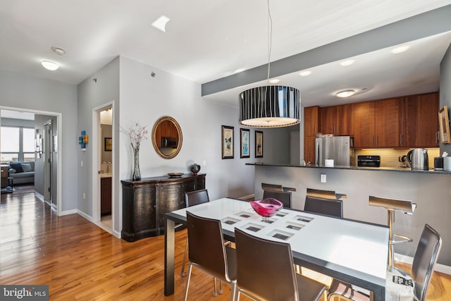 dining space featuring baseboards and light wood finished floors