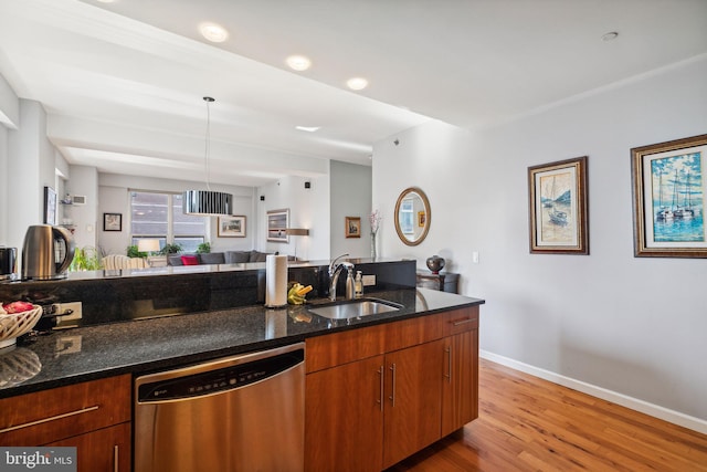 kitchen with a sink, light wood-style floors, dishwasher, dark stone countertops, and pendant lighting