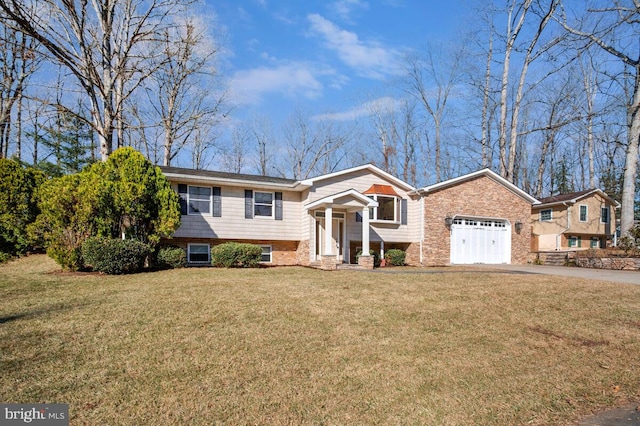 raised ranch with brick siding, aphalt driveway, an attached garage, and a front yard