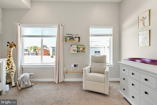 living area featuring baseboards and light carpet