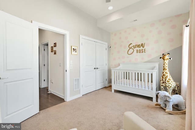 carpeted bedroom with baseboards, visible vents, a crib, and a closet