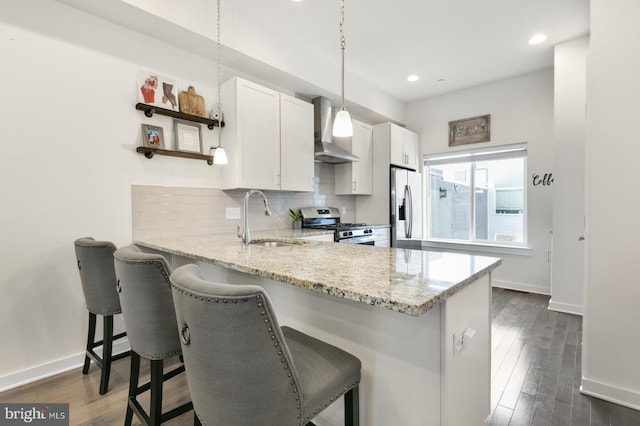 kitchen featuring backsplash, open shelves, wall chimney range hood, appliances with stainless steel finishes, and a sink