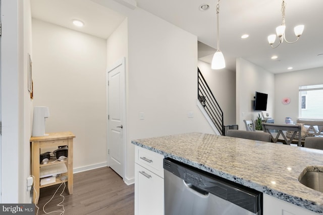 kitchen featuring light wood-type flooring, light stone counters, hanging light fixtures, white cabinets, and stainless steel dishwasher