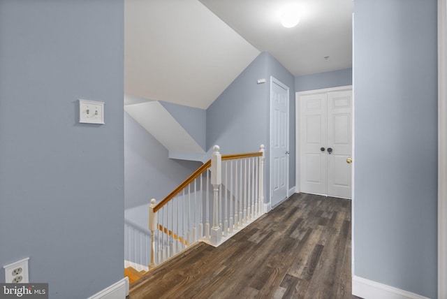 hallway featuring dark wood-style floors, baseboards, and an upstairs landing