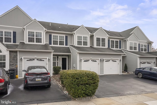 view of property with an attached garage, driveway, and roof with shingles