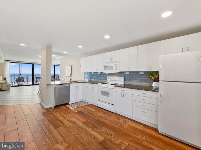 kitchen featuring white appliances, sink, backsplash, white cabinetry, and hardwood / wood-style flooring