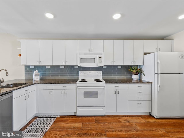 kitchen with sink, white appliances, dark stone counters, and white cabinetry