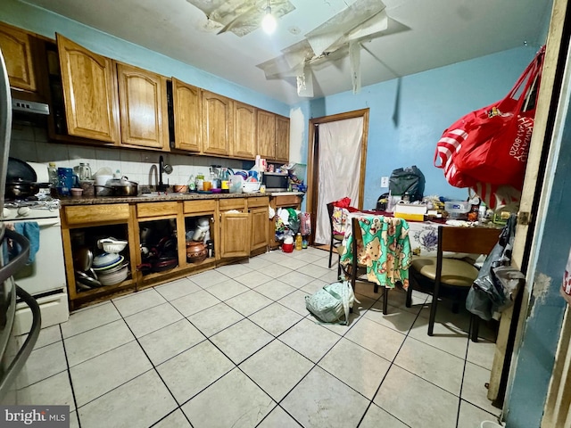 kitchen featuring sink, light tile patterned flooring, white gas stove, ceiling fan, and tasteful backsplash