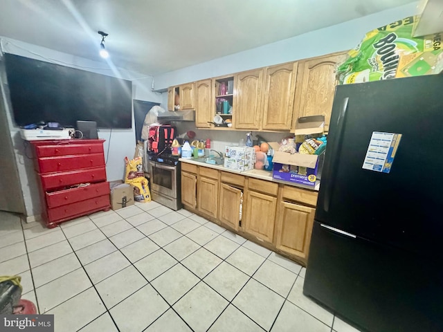 kitchen with electric range, light tile patterned flooring, and black fridge