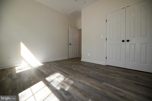 unfurnished bedroom with baseboards, a closet, and dark wood-style floors