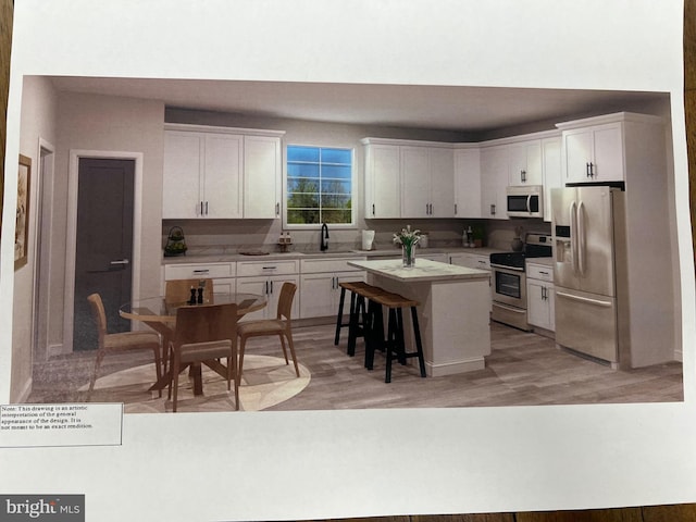 kitchen with a breakfast bar, a sink, a kitchen island, stainless steel appliances, and white cabinets