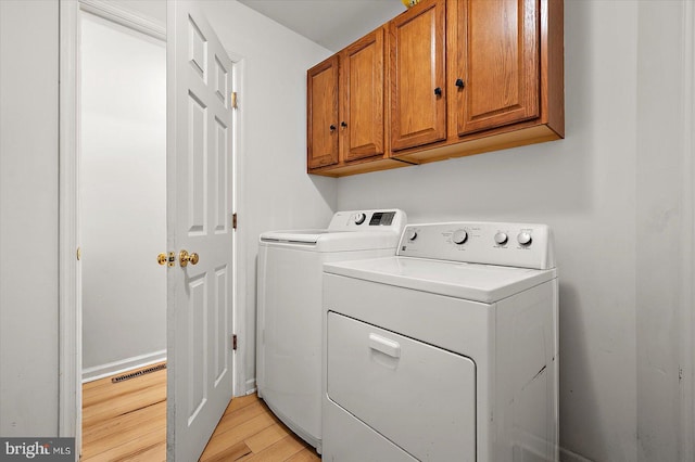 laundry area with light wood-style flooring, cabinet space, visible vents, and washing machine and clothes dryer