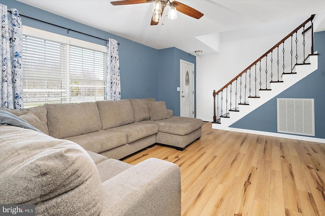 living room featuring stairway, a ceiling fan, wood finished floors, visible vents, and baseboards