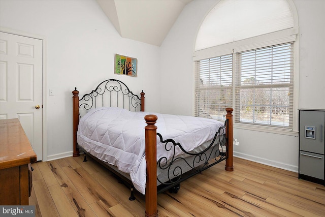 bedroom featuring baseboards, lofted ceiling, and light wood finished floors