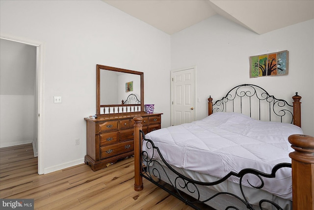 bedroom featuring light wood-type flooring, lofted ceiling, and baseboards