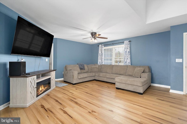living area with ceiling fan, baseboards, and light wood-style flooring