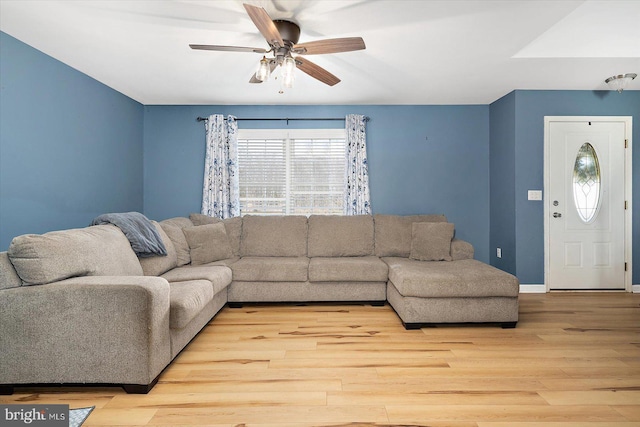 living area featuring wood finished floors, baseboards, and ceiling fan