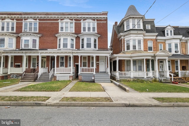 townhome / multi-family property with covered porch and brick siding