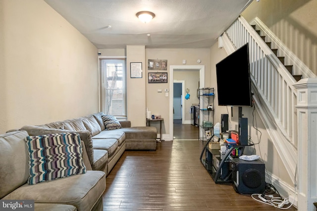 living room with dark wood-type flooring, stairway, and baseboards