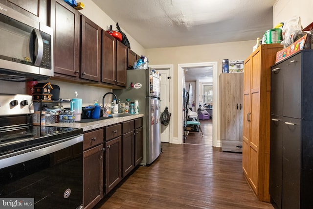 kitchen with dark wood-style floors, appliances with stainless steel finishes, light countertops, dark brown cabinets, and a sink