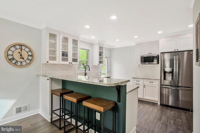 kitchen featuring white cabinets, visible vents, stainless steel appliances, dark wood-type flooring, and a peninsula