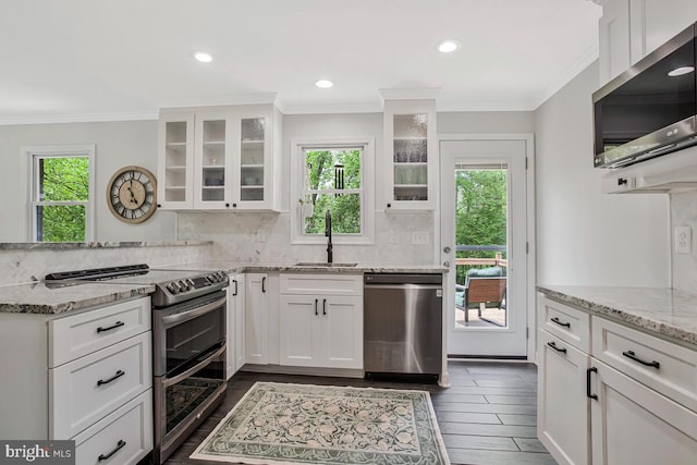 kitchen with white cabinets, stainless steel appliances, ornamental molding, and a sink