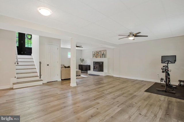 unfurnished living room with baseboards, ceiling fan, light wood-style floors, and plenty of natural light