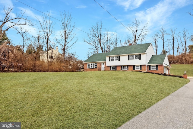 view of front of home with a front lawn, a chimney, and brick siding