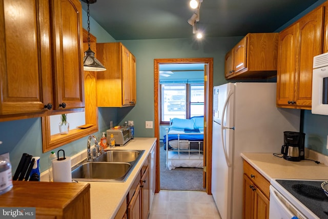 kitchen with white appliances, track lighting, pendant lighting, and sink