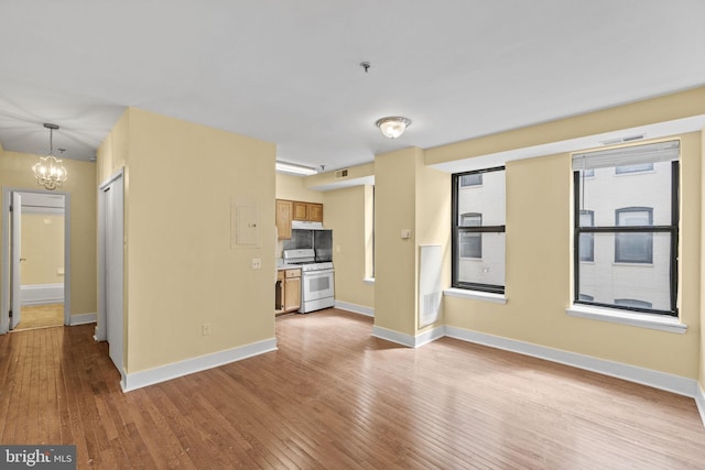 unfurnished living room with light wood-type flooring and an inviting chandelier