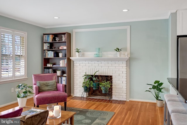 living area featuring a brick fireplace, light hardwood / wood-style floors, and ornamental molding