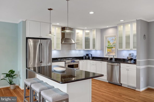 kitchen with high end appliances, white cabinets, pendant lighting, a kitchen island, and light wood-type flooring