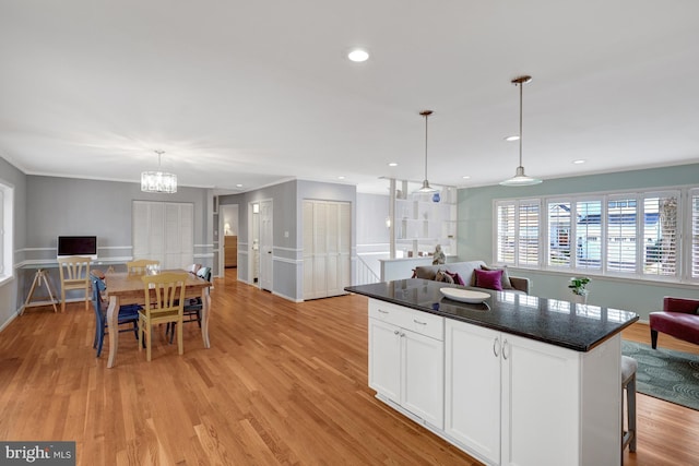 kitchen with light hardwood / wood-style flooring, a breakfast bar, white cabinetry, a kitchen island, and decorative light fixtures