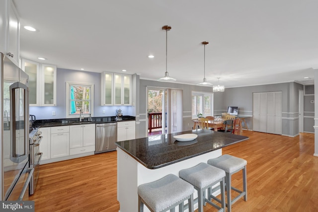 kitchen with decorative light fixtures, a kitchen island, sink, white cabinets, and premium appliances