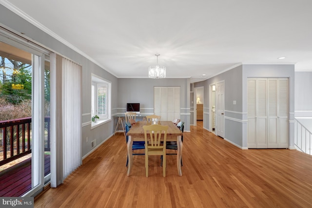 dining room with light hardwood / wood-style floors, an inviting chandelier, and crown molding