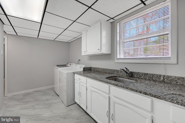 clothes washing area featuring sink, cabinets, and independent washer and dryer