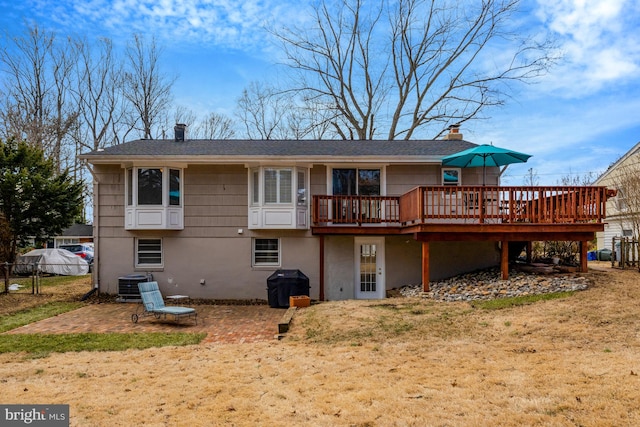 back of property featuring central air condition unit, a lawn, a wooden deck, and a patio area