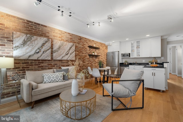 living area with light wood-style floors, recessed lighting, crown molding, and brick wall