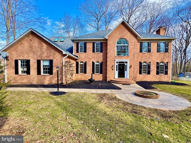 back of property with a chimney, a lawn, and brick siding