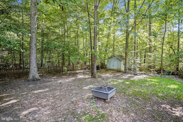 view of yard featuring a storage shed, an outdoor fire pit, fence, and an outdoor structure