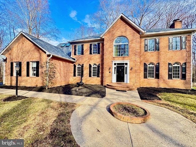 view of front of house with brick siding and a chimney