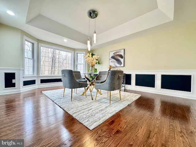 dining room featuring recessed lighting, a decorative wall, wainscoting, dark wood-style floors, and a tray ceiling