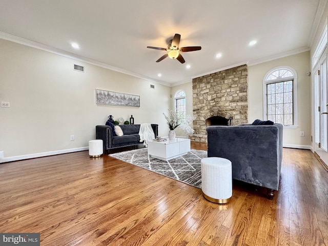 living area featuring visible vents, crown molding, a fireplace, and wood finished floors