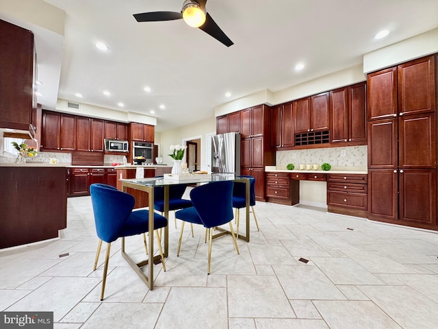 kitchen with light countertops, appliances with stainless steel finishes, dark brown cabinets, a center island, and built in desk