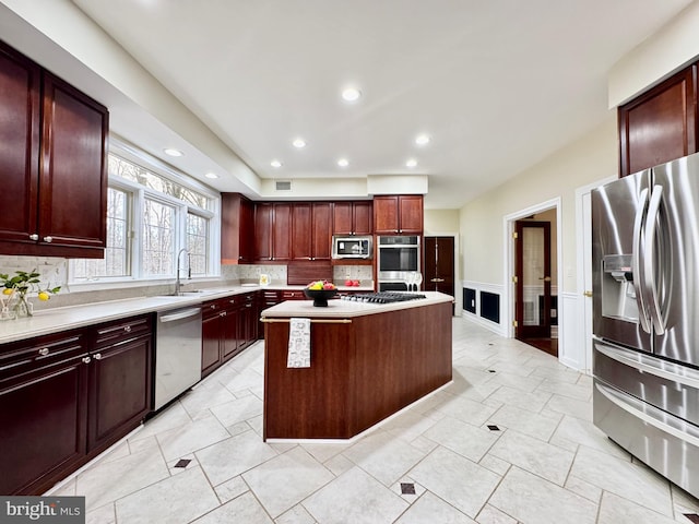 kitchen featuring a center island, stainless steel appliances, light countertops, a sink, and dark brown cabinets