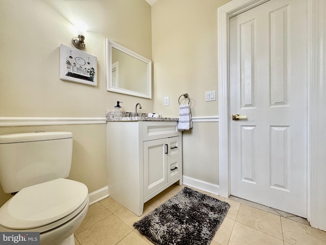 bathroom featuring toilet, baseboards, and vanity